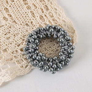 Detailed view of grey faux pearl beaded elastic hair tie on a white lace background