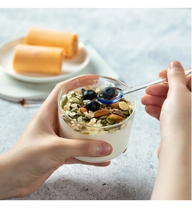 Dettaglio di un cucchiaio in vetro termoresistente con punta blu in una ciotola di cereali