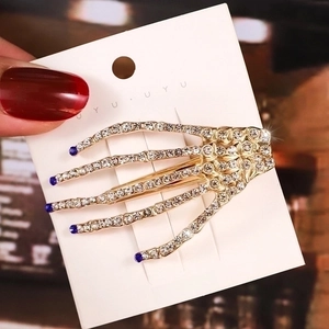 Skeleton hand hair clip with sparkling white and blue rhinestones on gold metal base
