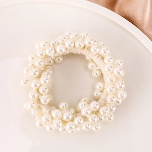 Elegant white pearl hair tie and bracelet with elastic fabric base on a tray