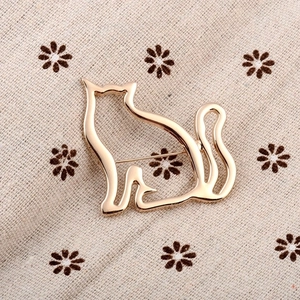 Cute hollow cat brooch pin in golden metal finish on elegant floral background