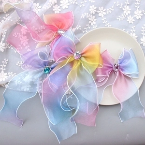 Rainbow gradient tulle bow hair clips with crystal center on a white lace background
