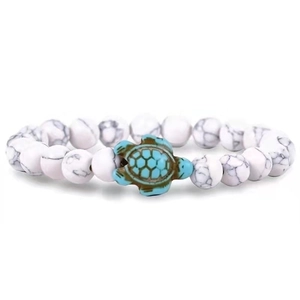 Detail of beaded bracelet with white turquoise stones and green sea turtle charm