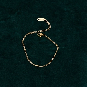 Detailed close-up of 18K gold bean bracelet featuring K18 engraved tag and lobster clasp