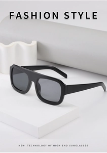Close-up of flat top square sunglasses with black frames on geometric white props