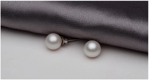 Detailed view of 8mm round white pearl earrings on elegant grey silk fabric texture