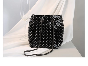 Detail of elegant black rhinestone bucket bag with dark metal snake chain and silver crystals