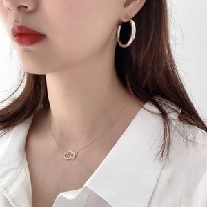 Detailed view of silver C-shape hoop earrings and heart pendant necklace on model