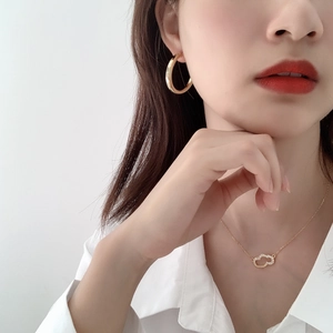 Close-up of elegant gold layered heart pendant necklace and matching C-shape hoop earrings