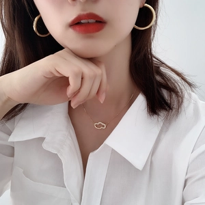 Close-up of minimalist large golden C-shaped hoop earrings worn by a model in white