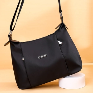 Black lightweight nylon crossbody bag with adjustable strap and metal hardware detail