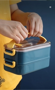 Detail view of double-layer lunch box featuring ergonomic yellow handle and side locks