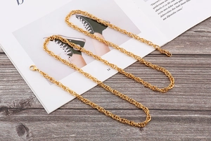 Flat lay detail of a long golden chain link necklace on a dark wood and magazine background