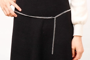 Detailed view of silver Cuban link waist chain on black dress with adjustable extension