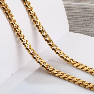 Polished gold Cuban link chain necklace with flat NK links for women on wooden surface