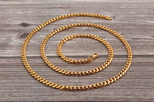 Detail of a golden cuban link chain with a secure lobster clasp on a dark wooden surface