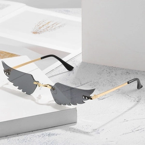 Detail of wing-shaped sunglasses with dark gray lenses and golden metal frame
