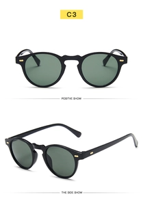 Detail view of vintage black small frame sunglasses with dark green lenses and gold accents
