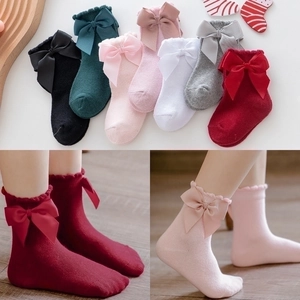 Detail of girls' cotton socks featuring large bows and ruffled edges in seven colors