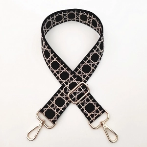 Close-up of adjustable woven strap with beige geometric lattice pattern and gold hooks