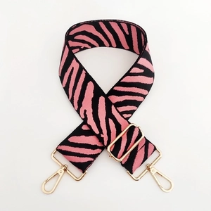 Detail of pink and black zebra pattern woven shoulder strap with gold swivel hooks