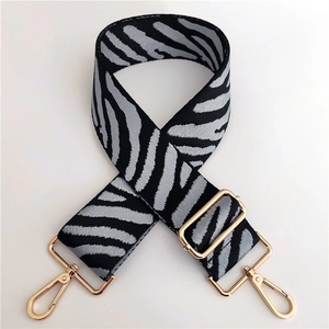 Detail of adjustable zebra print canvas strap with polished gold-tone metal lobster clasps