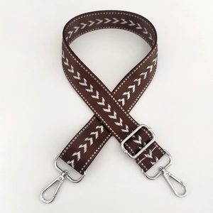 Close-up of adjustable brown nylon bag strap with white arrow pattern and silver hardware