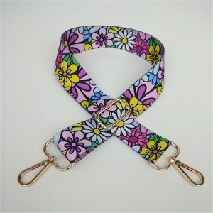 Close-up of adjustable wide handbag strap with colorful floral patterns and gold metal buckles