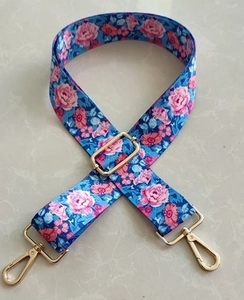 Detail of adjustable blue bag strap with pink floral pattern and gold metal hooks