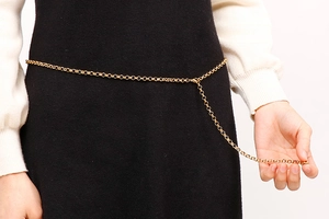 Detail of a golden thin chain belt with circular interlocking rings and adjustable tail
