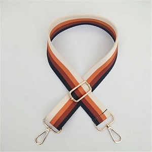 Close-up of a wide woven colorful striped replacement bag strap with golden metal hooks