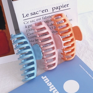 Three large matte candy-colored hair claw clips in blue, pink, and orange on minimalist background