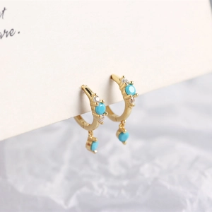 Macro shot of gold S925 sterling silver huggie earrings with turquoise and zircon