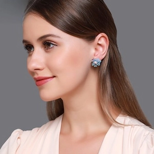 Détail d'une boucle d'oreille marguerite bleue aux pétales délicats portée par un mannequin