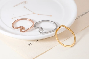 Detailed view of wave-shaped stainless steel rings in gold, silver, and rose gold finishes