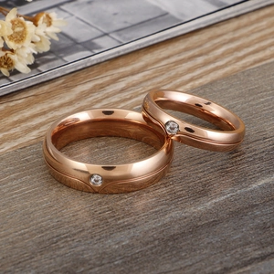 Polished rose gold couple rings set with cubic zirconia on a rustic wooden base