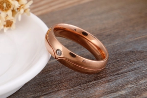 Close-up of a rose gold ring with wave texture and a sparkling small diamond inlay