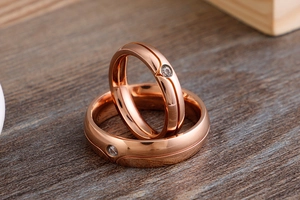 Detail of rose gold couple rings with streamlined grooves and center-set zircon stones