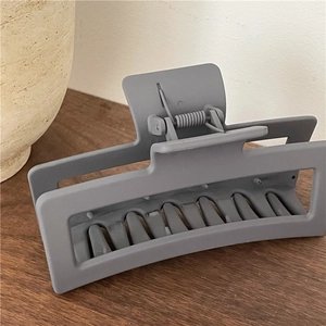 Matte grey rectangular claw clip for thick hair shown on a wooden background