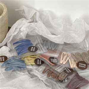 Detail of colorful matte drop hair clips in handmade packaging on white paper
