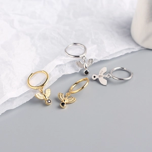 Macro detail of S925 sterling silver hoop earrings with eagle charms and black gemstone