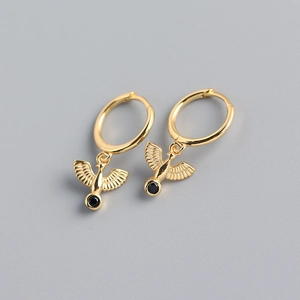 Detail of gold-plated silver hoop earrings featuring bird charms with black gemstone accents