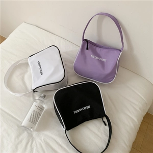 Three minimalist nylon shoulder bags in white, purple, and black on a soft fabric background