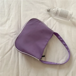 Detail of purple nylon underarm bag with white trim on a white fabric background