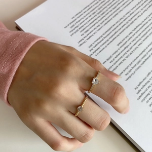Detailed view of elegant gold-plated rings with heart and round zircon stones on a model