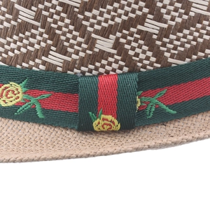 Macro detail of a classic straw fedora hat featuring a green and red striped floral band