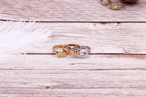 Détail de bagues en forme de cœur en or, or rose et argent sur une surface en bois
