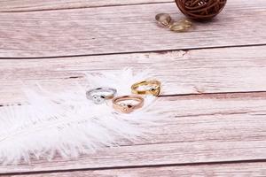 Détails des bagues cœur en or, argent et or rose sur une plume blanche douce et élégante