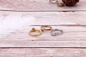 Trois bagues en forme de cœur en or, or rose et argent avec zircons sur bois