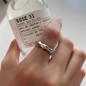 Detail of minimalist 925 silver ring with organic lava texture on hand holding a perfume